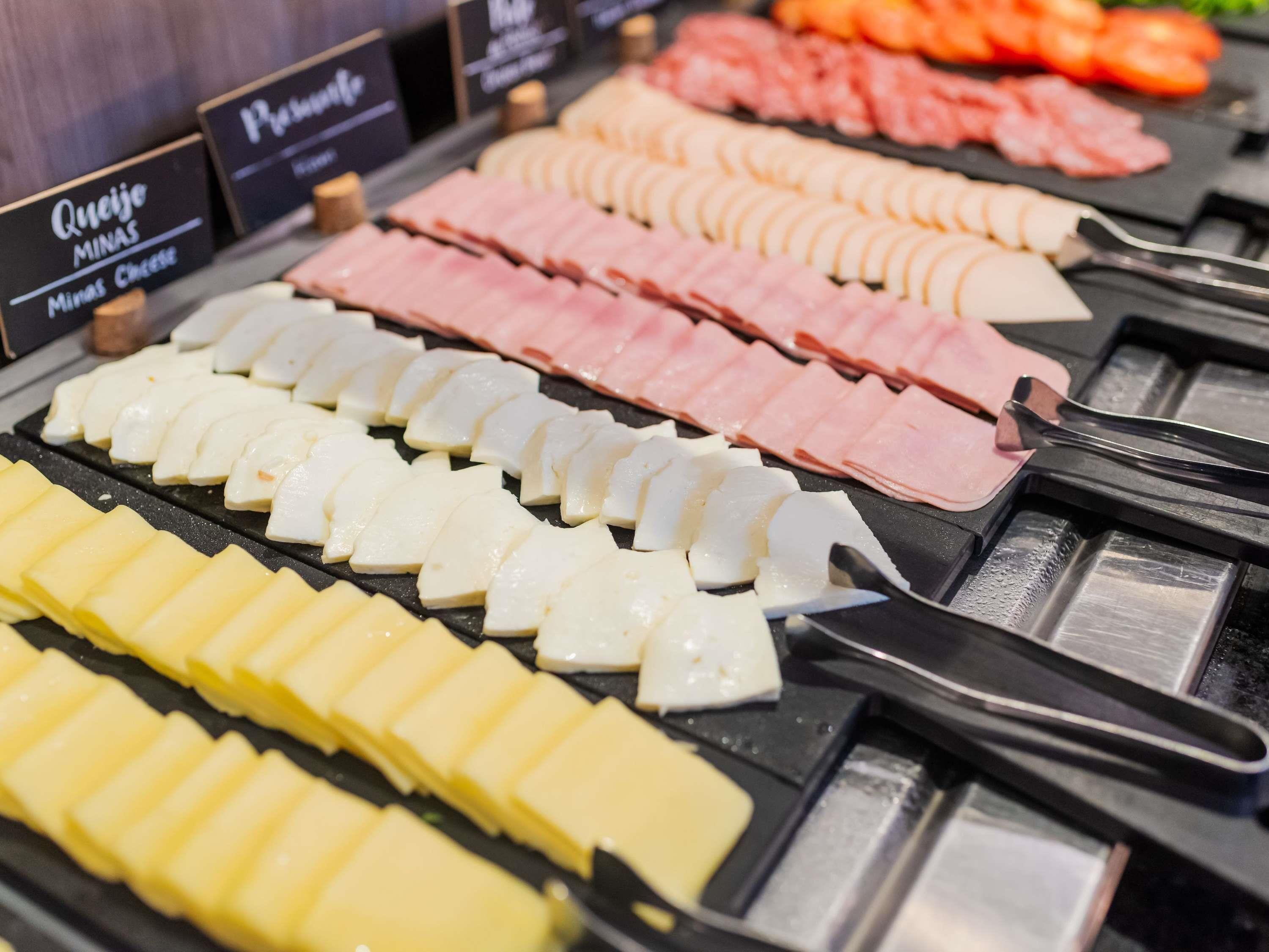 A variety of sliced meats and cheeses on a display counter.