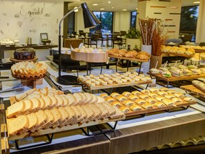 Un bufé con diferentes opciones de comida, como pan, pasteles y sándwiches.