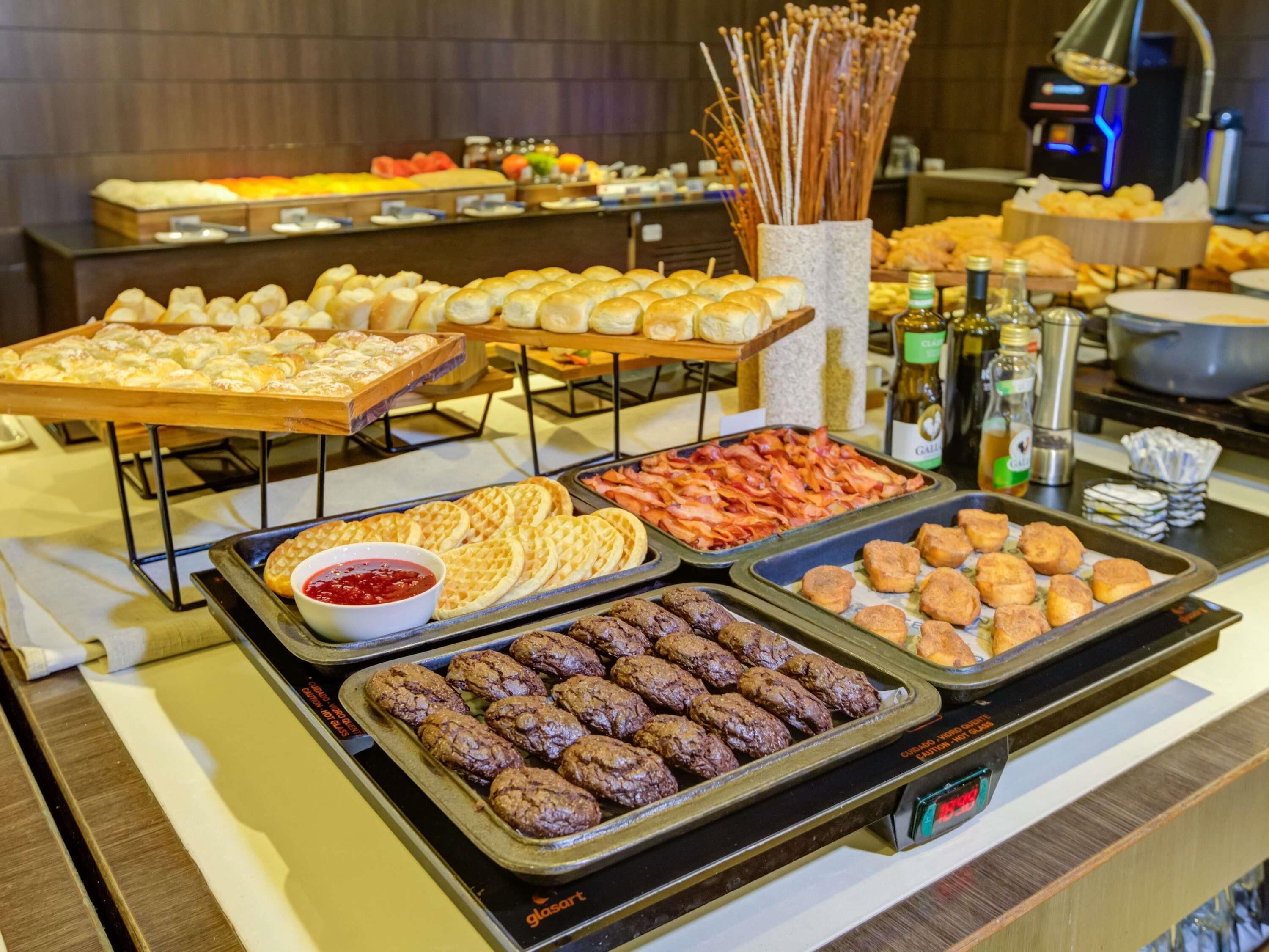 Un buffet proposant une variété de plats, notamment des gaufres, du bacon et des boulettes de viande.