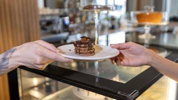 A person holding a dessert on a plate.