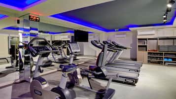 Un gimnasio con cintas de correr, elípticas y un reloj digital que marca las 17:22:40.
