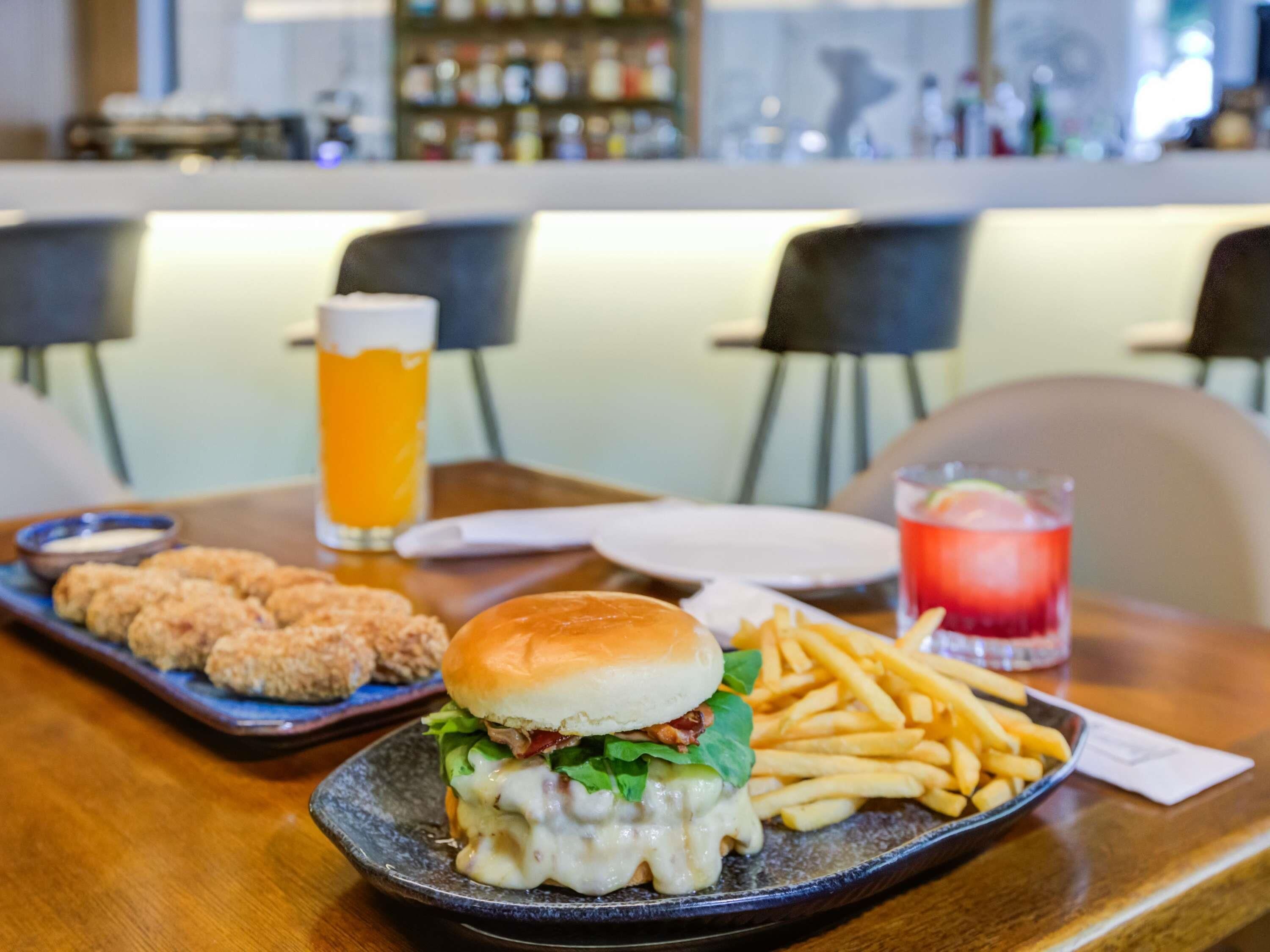 A meal with a burger, fries, and a drink on a table in a restaurant.
