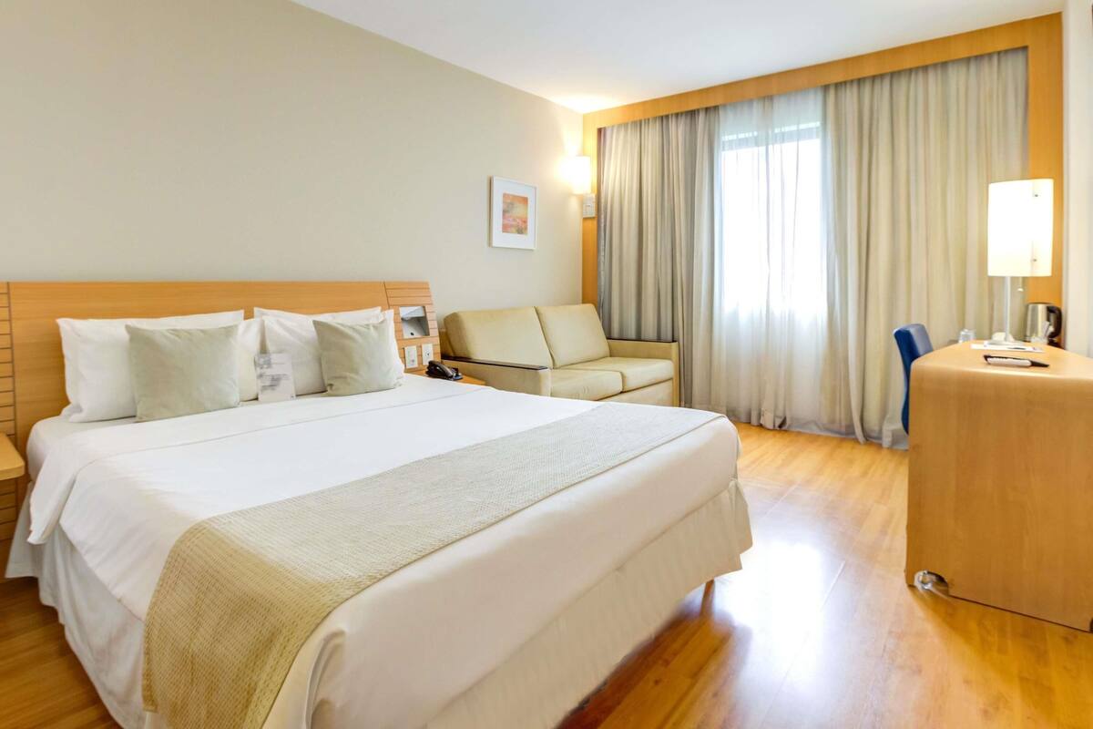 Una habitación de hotel con una cama grande, un escritorio, una silla y un sofá.