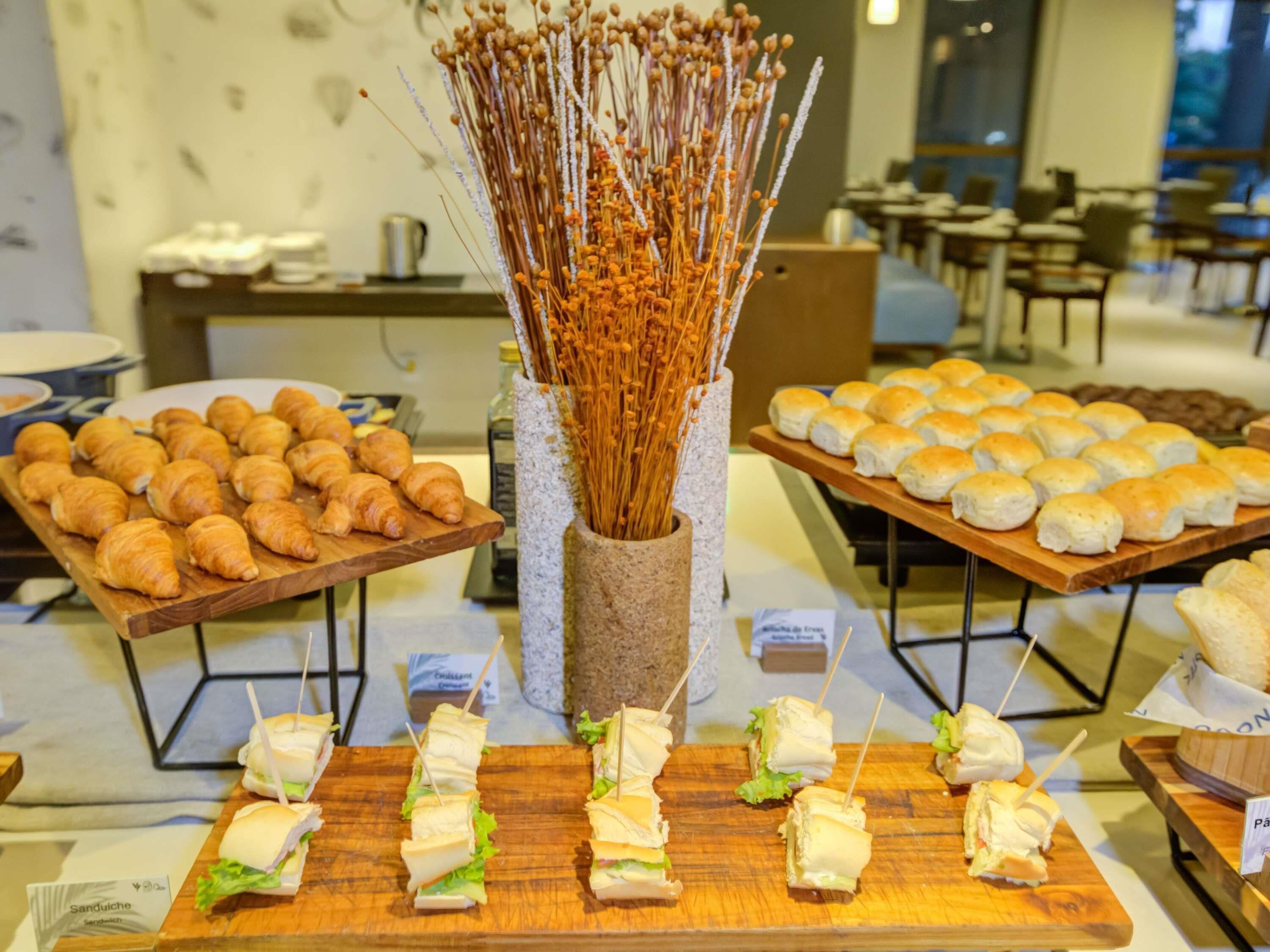 A buffet with croissants, sandwiches, and bread rolls.