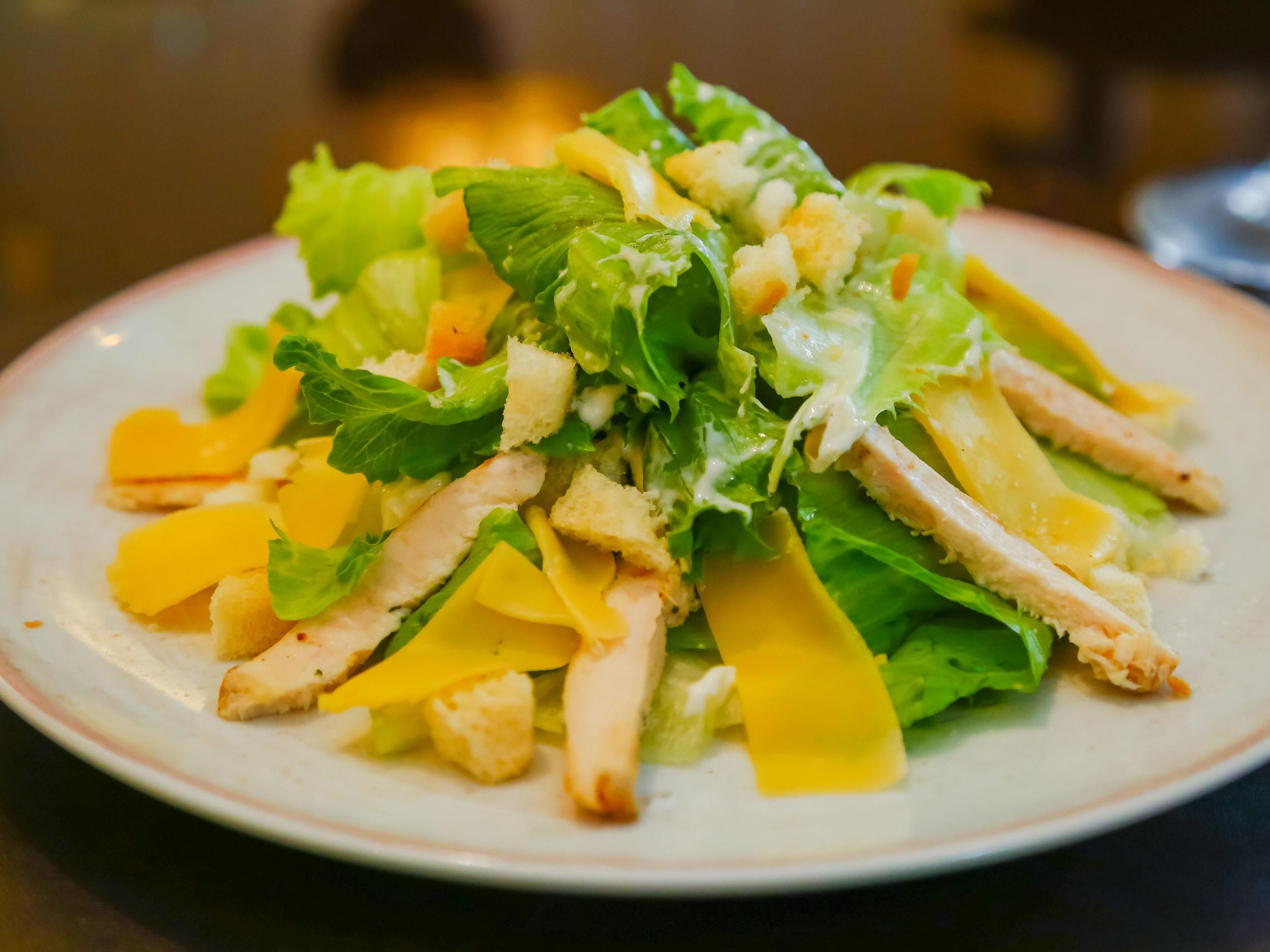 Uma salada com alface, croutons e frango.