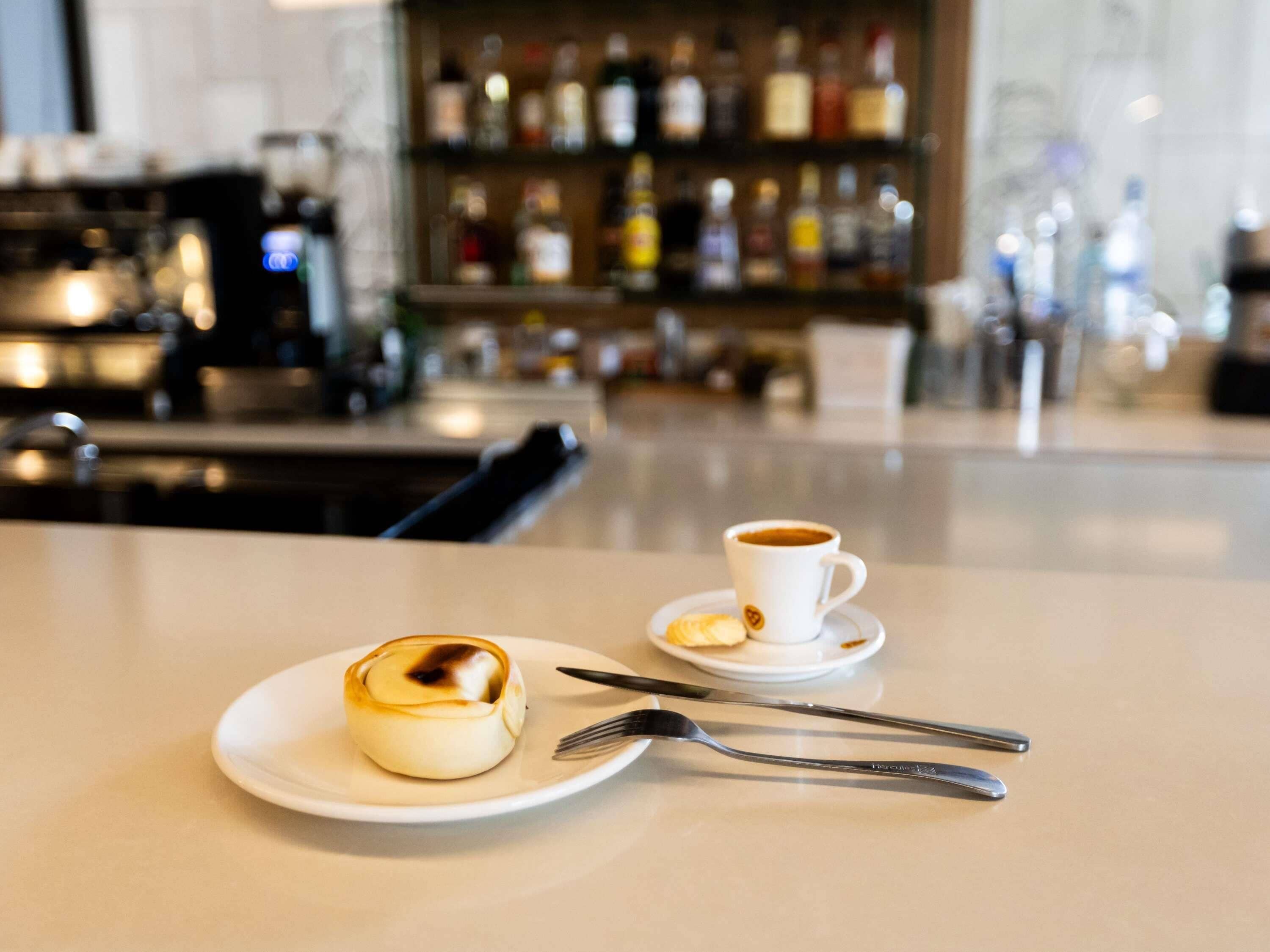 A dessert on a plate with a cup of coffee on a table in a cafe.