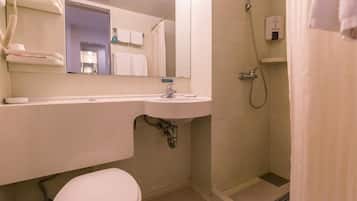 A small bathroom with a toilet, sink, and shower.