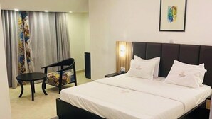 A modern bedroom with a large bed, a small table, and a chair. - Hotel Bon Voyage (Lagos)