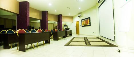 A conference room with rows of chairs, a projector screen, and a whiteboard.