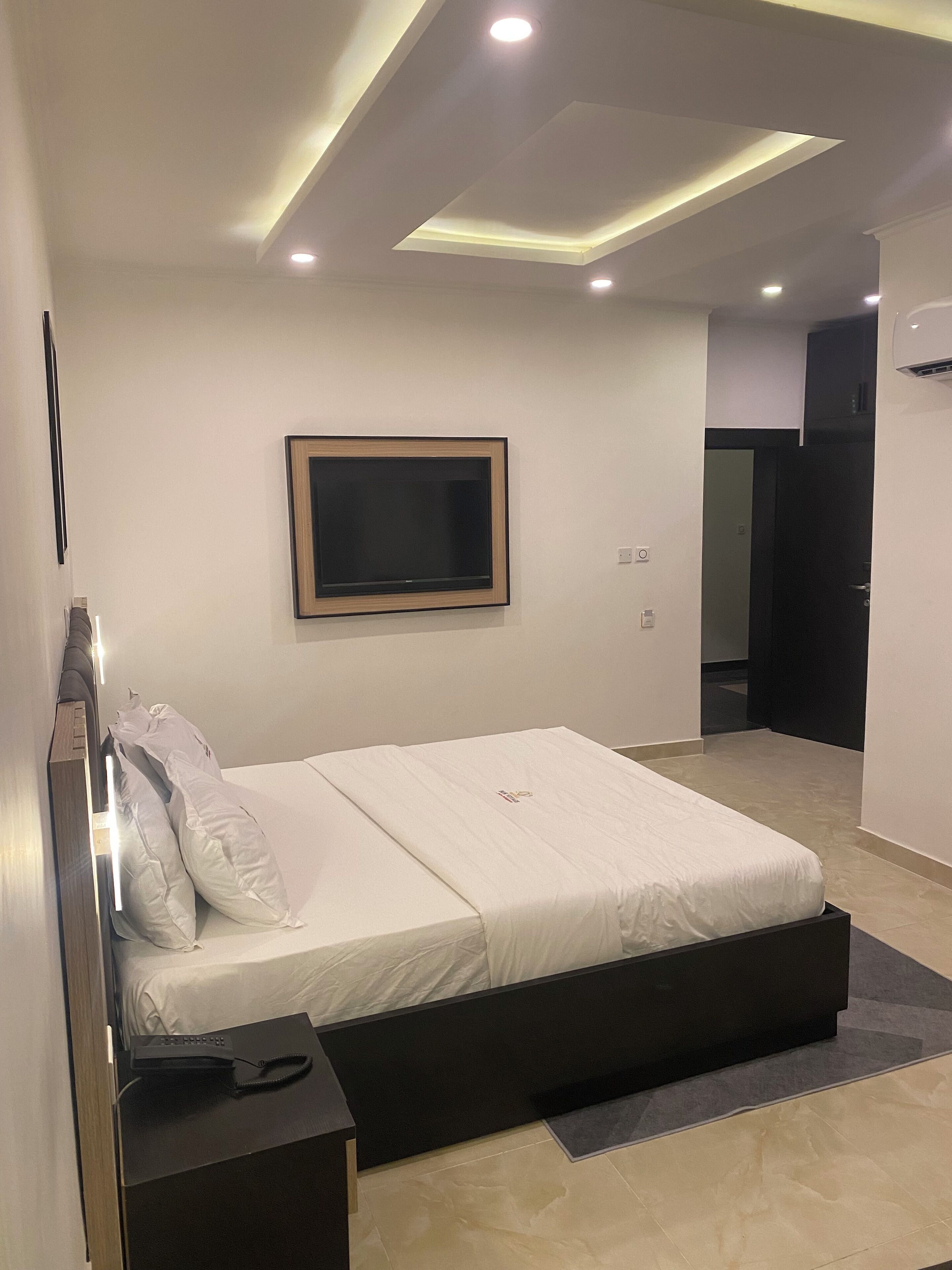 Un dormitorio moderno con cama, mesita de noche y televisor integrado.
