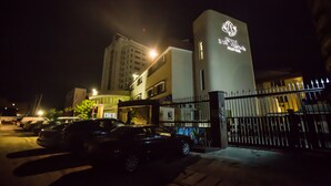 A hotel with a prominent sign, a gated parking area, and a building with multiple floors. - Hotel Bon Voyage (Lagos)