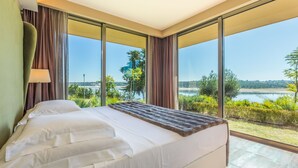 A modern hotel room with a large bed, a view of a lake, and a balcony. - AP Lago Montargil Conference & Spa (Ponte de Sor)