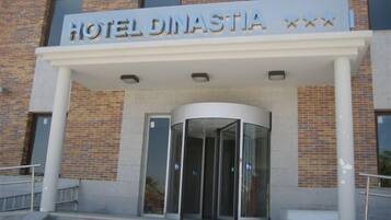 A hotel entrance with a revolving door and a sign that reads "HOTEL DINASTIA".
