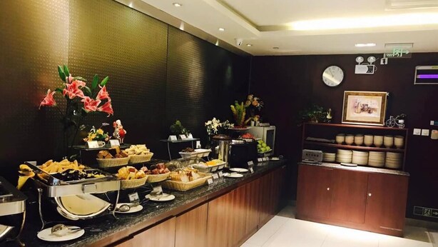 A buffet counter with various food items and a clock on the wall. - Jinjiang Inn Beijing Olympic Village Datun Road (Beijing)