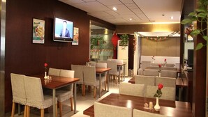 A restaurant with wooden tables and chairs, a TV screen, and a cozy interior. - Jinjiang Inn Beijing Olympic Village Datun Road (Beijing)