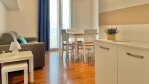 En moderne stue med sofa, et lille bord og et spiseområde med stole.