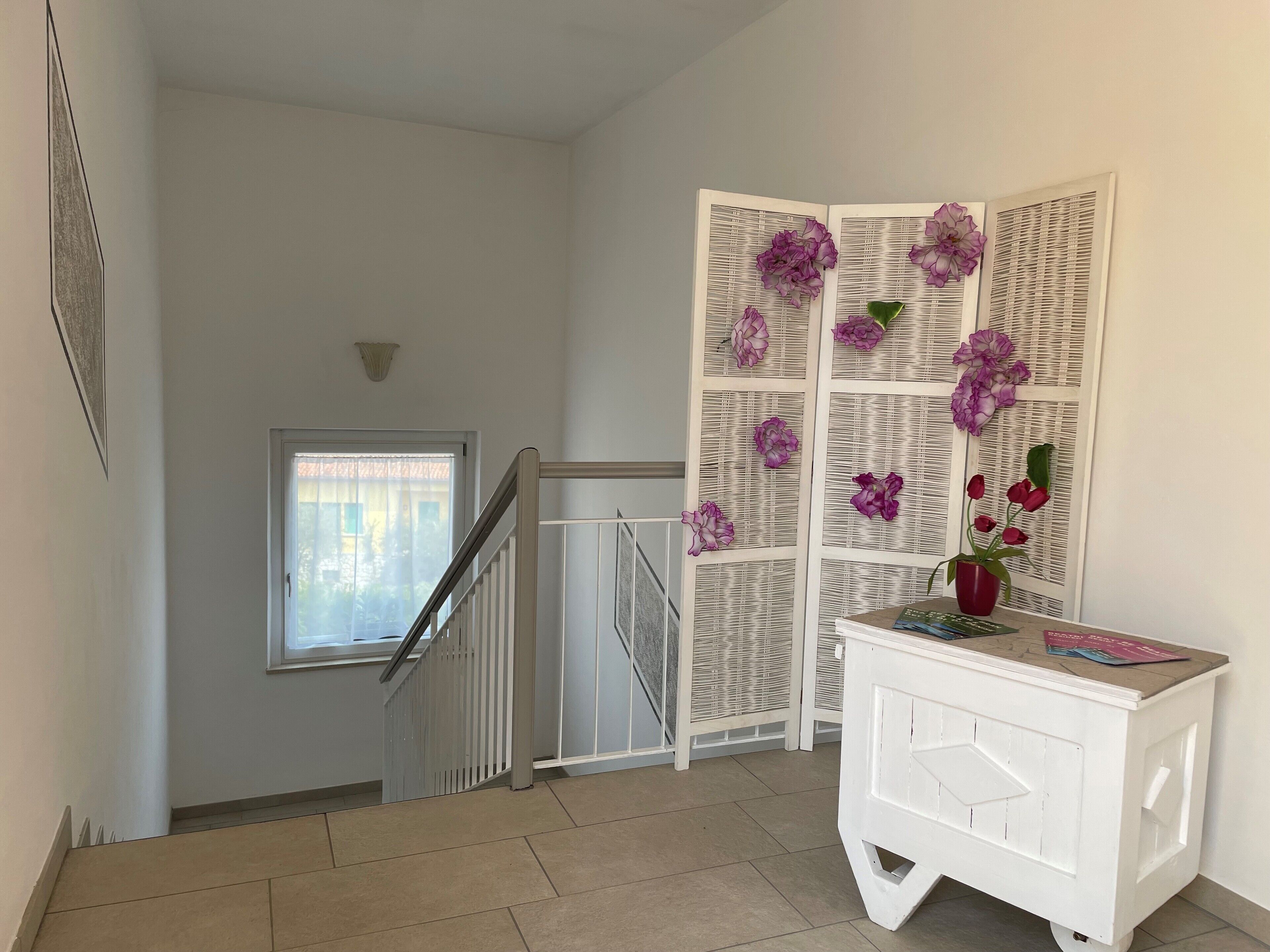 Un escalier avec une rampe blanche, un mur blanc et une fenêtre avec des stores.