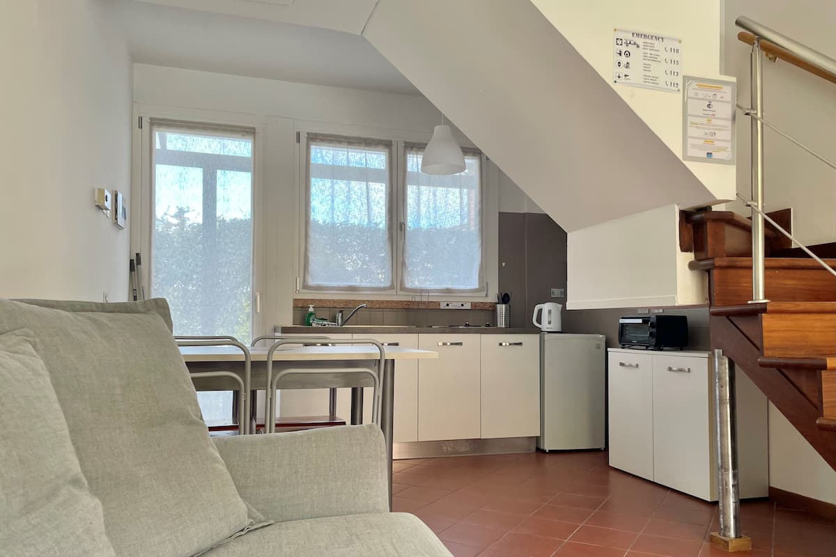 Una cocina moderna con comedor, una escalera y vistas al exterior.