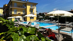 Et hotel med swimmingpool, liggestole og parasoller.