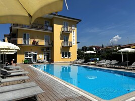 Una piscina al aire libre de temporada, sombrillas