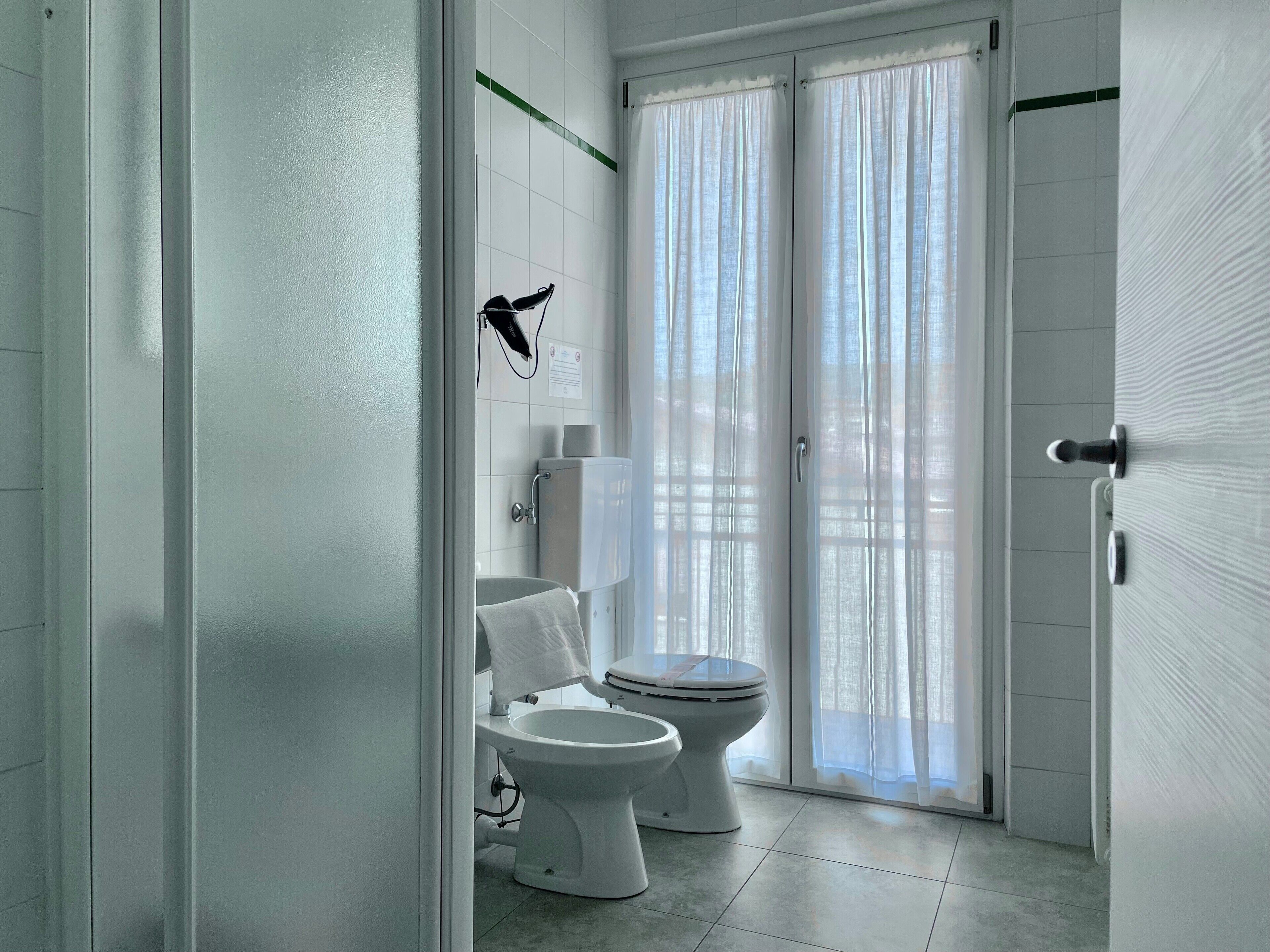 A modern bathroom with a toilet, bidet, and a towel rack.