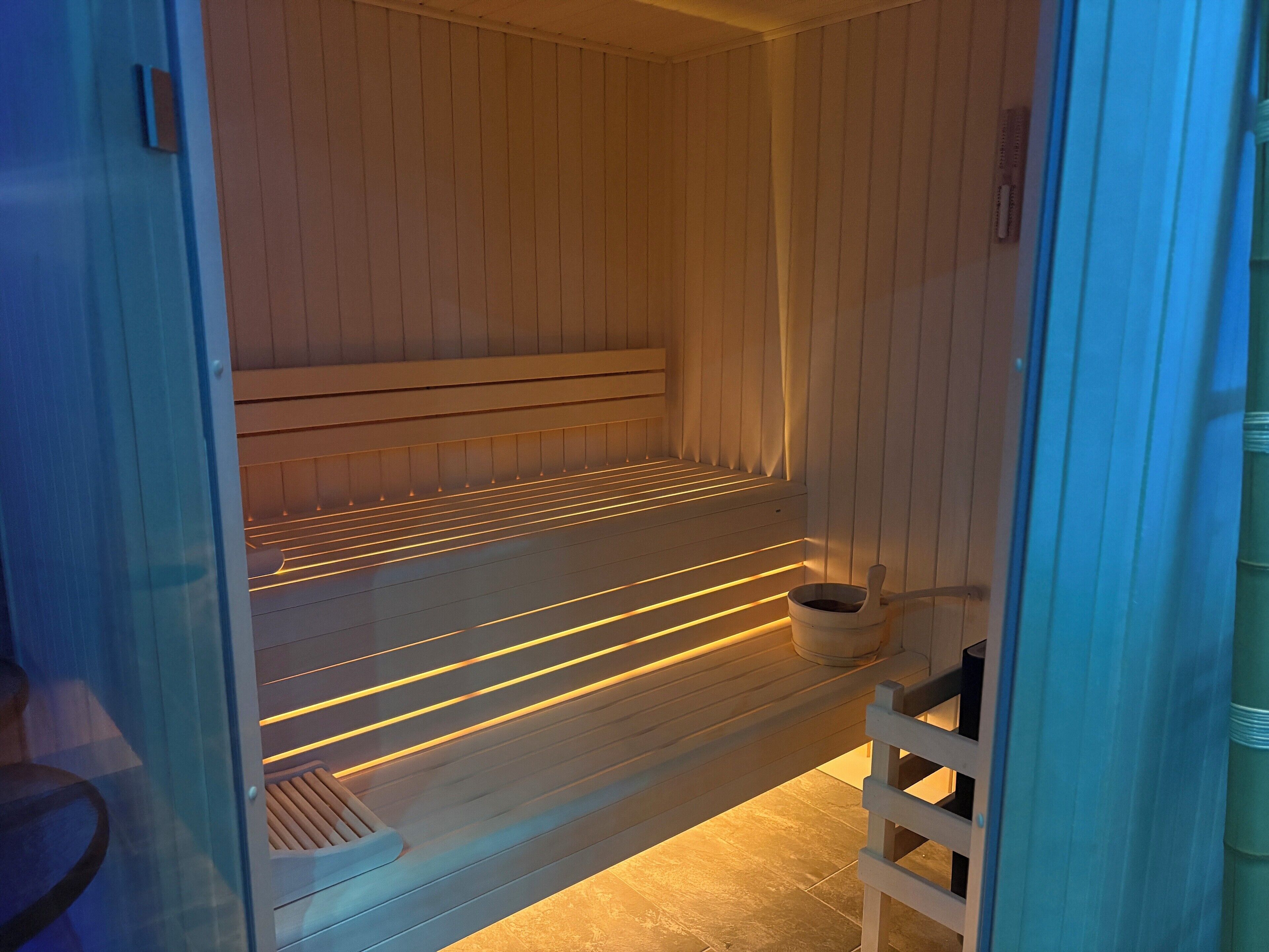 Una sauna con un banco de madera y un balde pequeño.