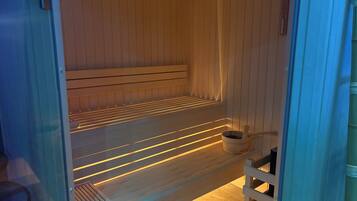 Una sauna con un banco de madera y un balde pequeño.