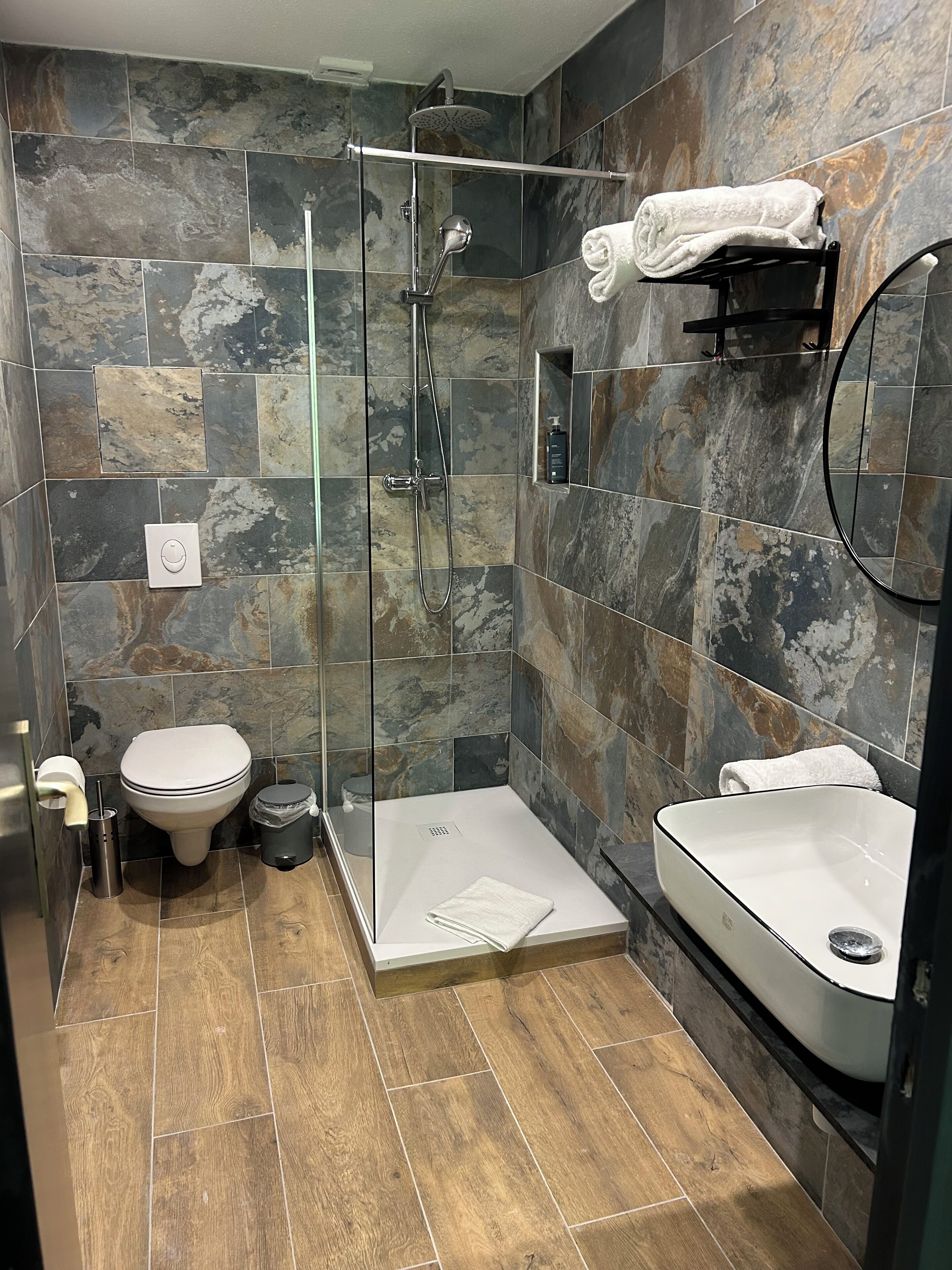 A modern bathroom with a glass-enclosed shower, a toilet, and a sink.
