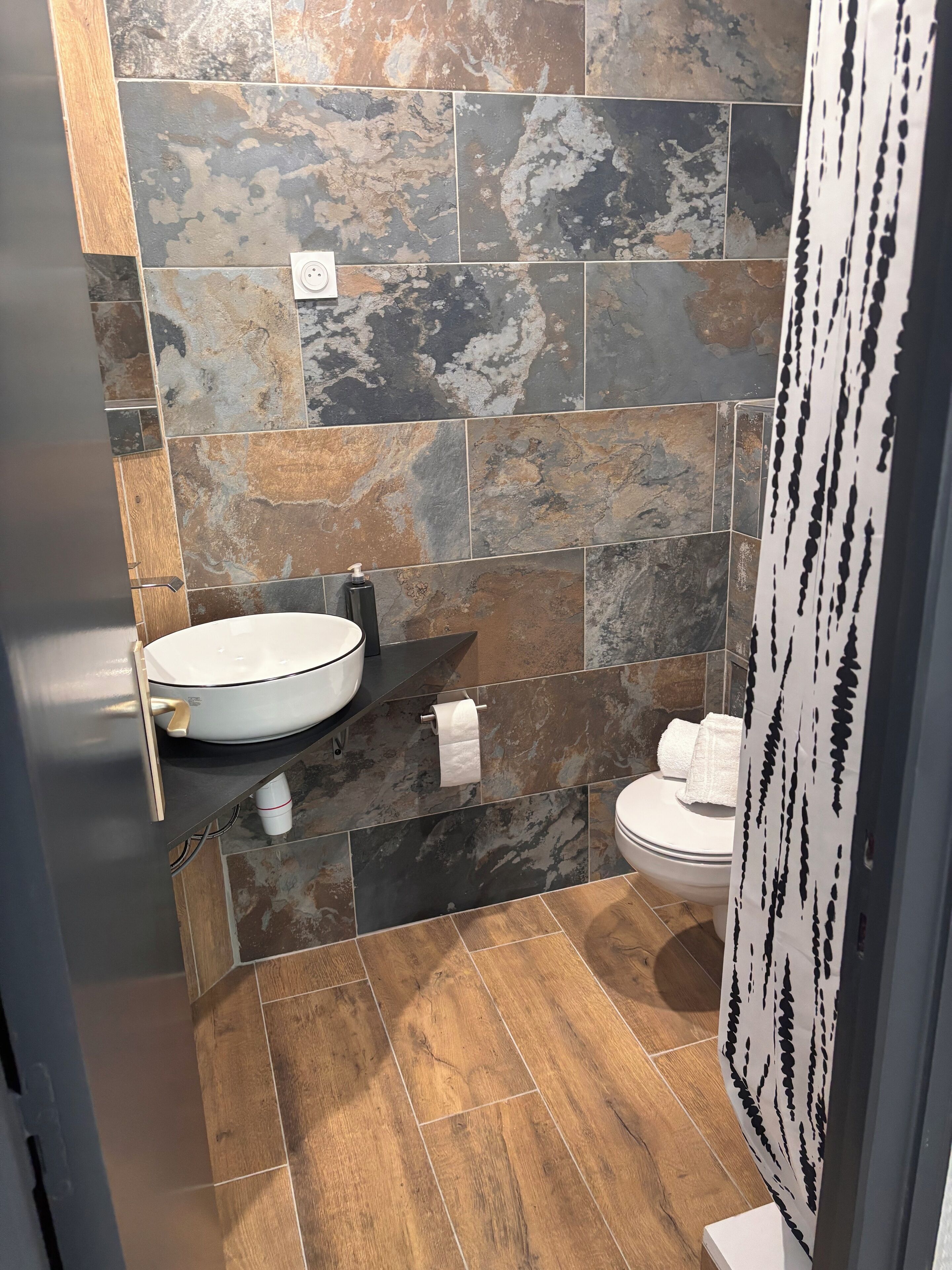 A bathroom with a white sink, a toilet, and a shower curtain with a black pattern.
