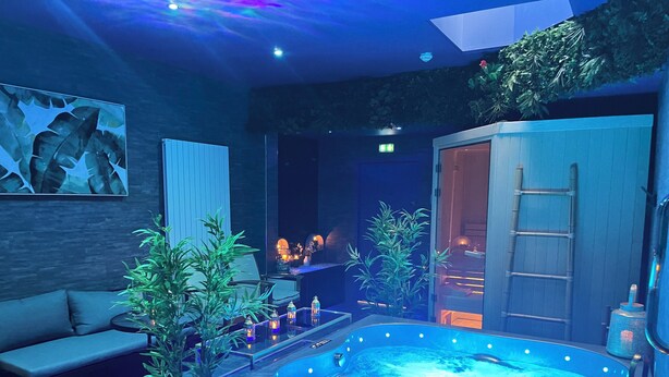 A modern spa area with a hot tub, seating, and ambient lighting. - Hôtel & SPA Le Gambetta, Centre-ville, Bergerac (Bergerac)
