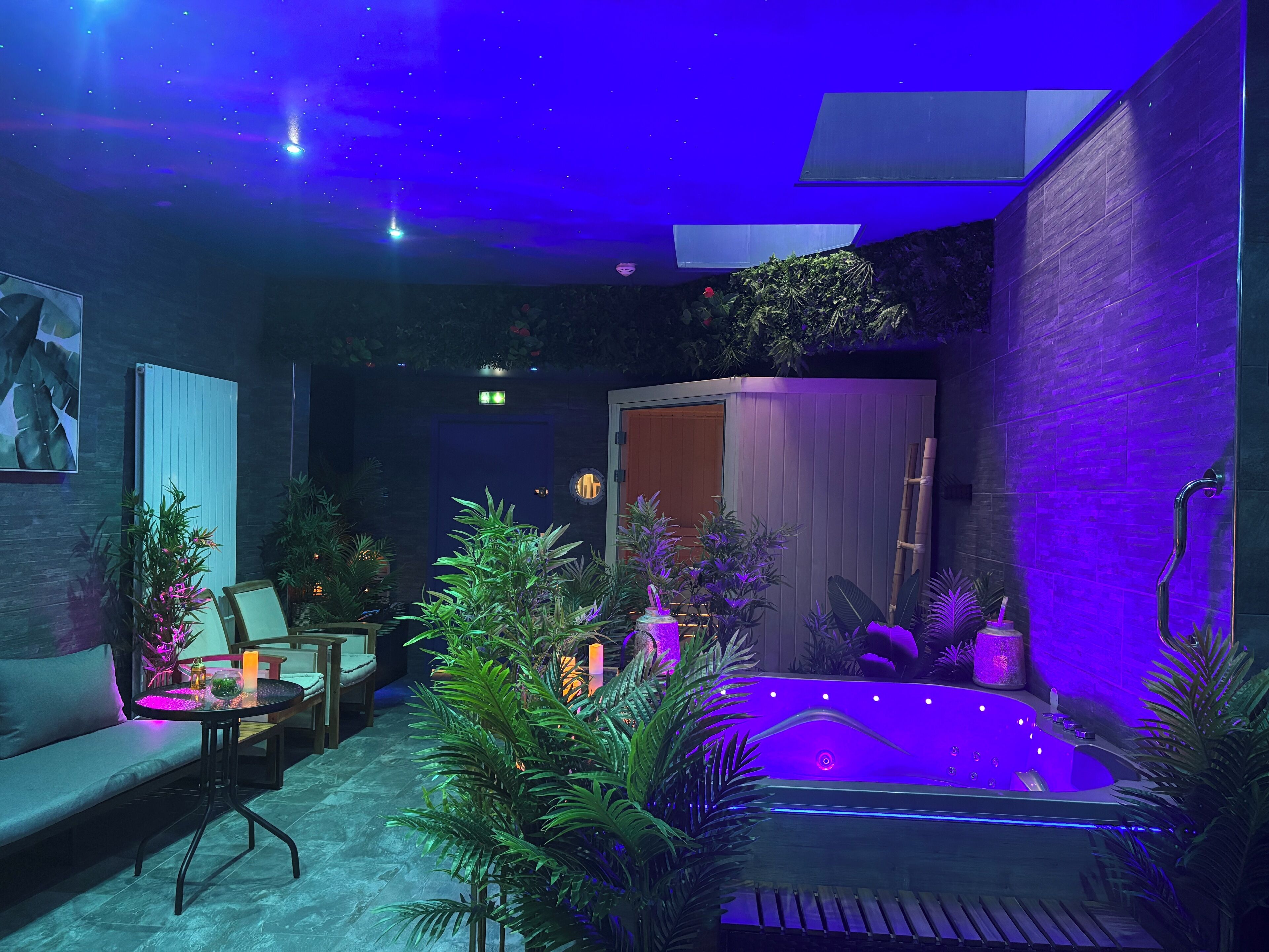 A modern spa area with a hot tub, seating, and lush greenery.