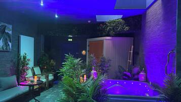 A modern spa area with a hot tub, seating, and lush greenery.
