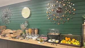 A buffet setup with various food items, a clock, and decorative wall art. - Hôtel & SPA Le Gambetta, Centre-ville, Bergerac (Bergerac)