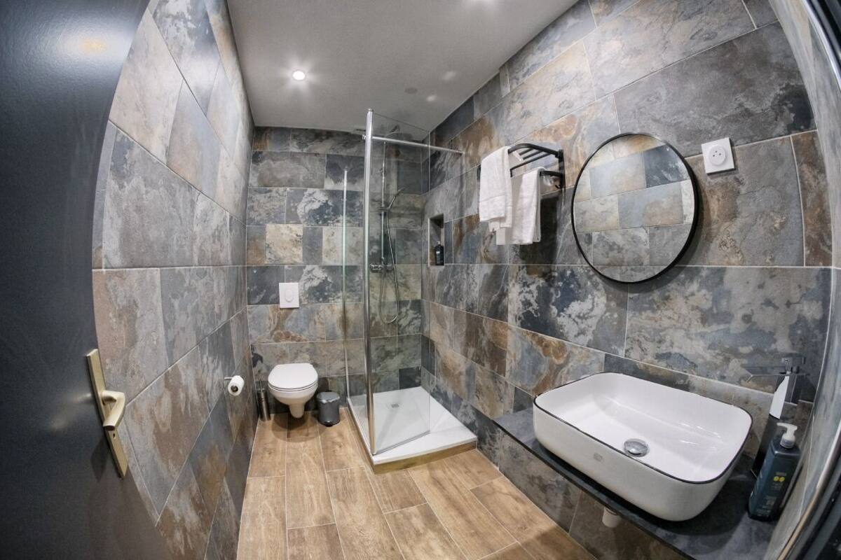 A modern bathroom with a glass-enclosed shower, a white sink, and a toilet.