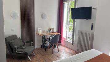 Una habitación de hotel con cama, escritorio con silla, televisor y ventana con vistas.