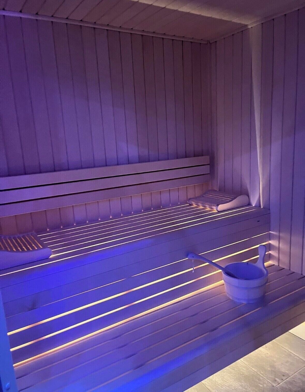 Una sauna con bancos de madera y un cubo.