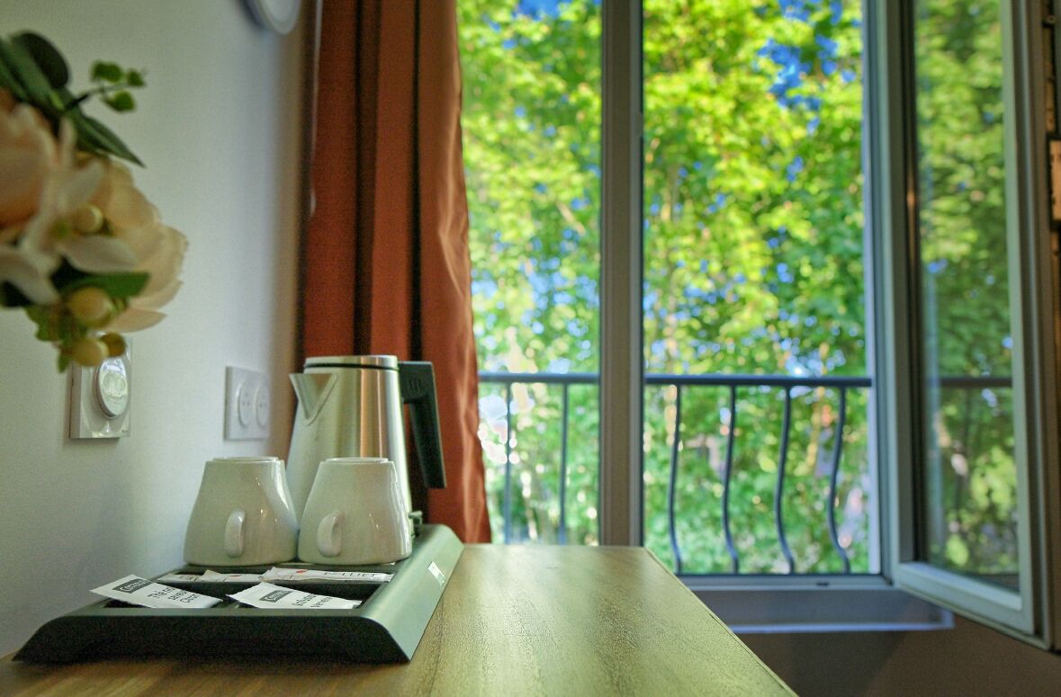 A room with a wooden table, a window with a view of trees, and a curtain.