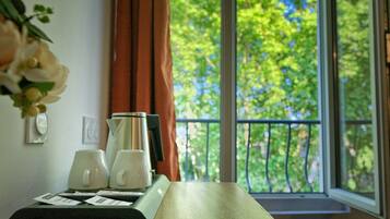 A room with a wooden table, a window with a view of trees, and a curtain.