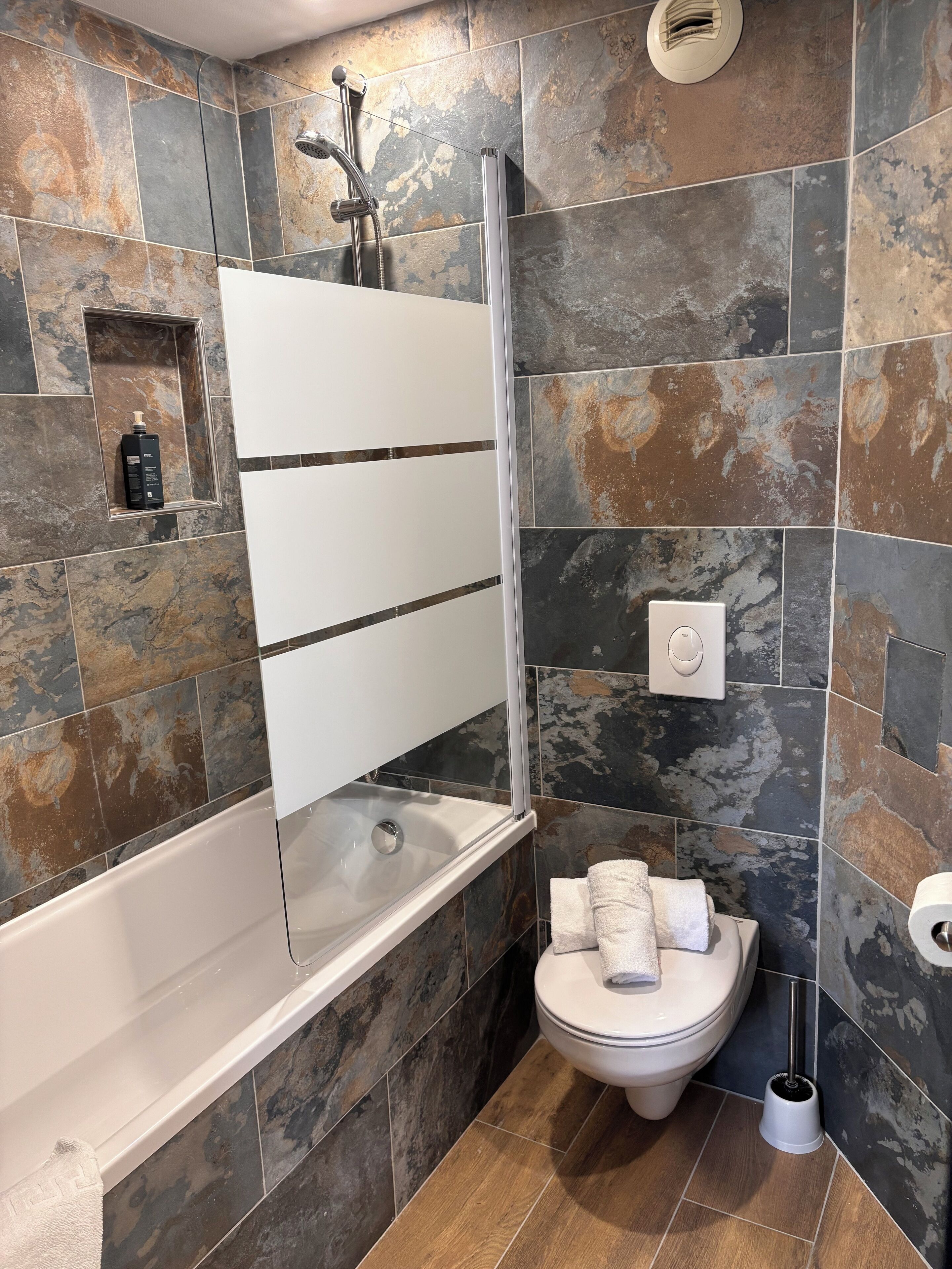 Een badkamer met een bad, toilet en douche.