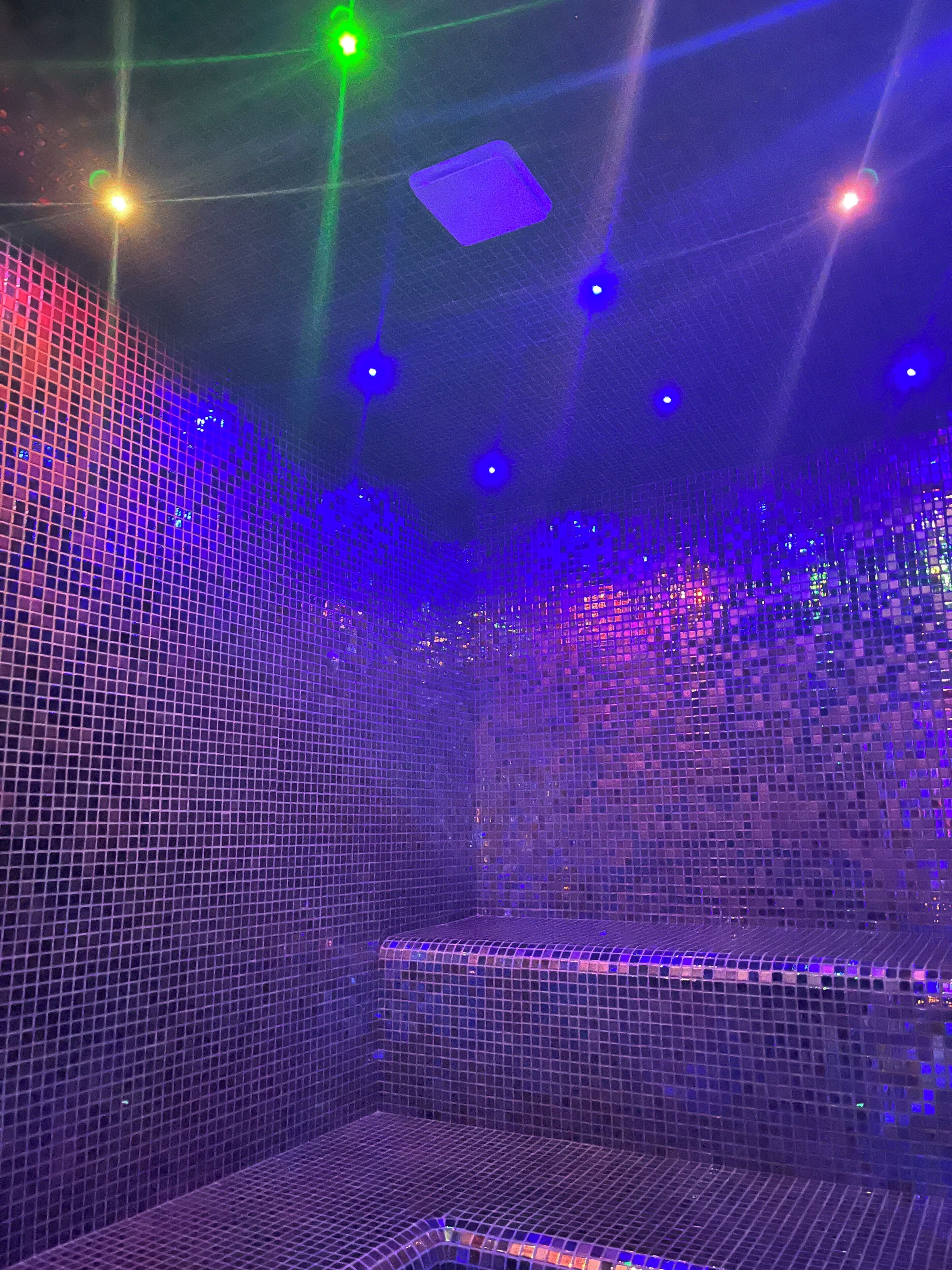Una habitación con piso y paredes de diseño cuadriculado, iluminada por luces multicolores.