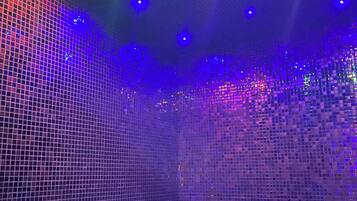 A room with a grid-patterned floor and walls, illuminated by multicolored lights.