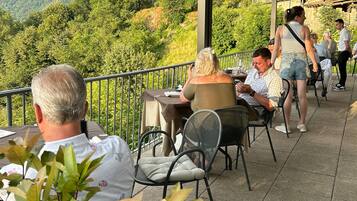 An outdoor patio with tables and chairs, overlooking a mountainous landscape.