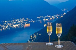 Two glasses of champagne on a table with a view of a lake and mountains at dusk. - Hotel Paradiso Como (Brunate)
