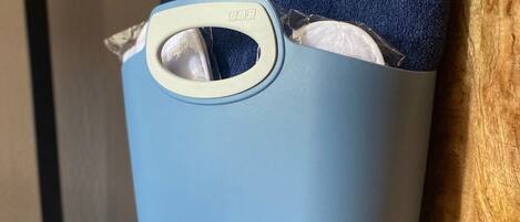 A blue storage bin with a handle, containing a towel and a white card with text.