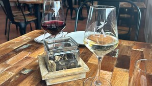 Una mesa de comedor con dos copas de vino, una con vino tinto y otra con vino blanco, y un pequeño recipiente con especias.