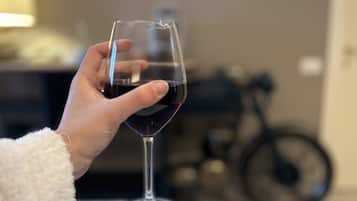Une main tenant un verre de vin, avec un arrière-plan flou représentant une pièce.