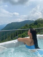 Une personne se détend dans un bain à remous, avec un paysage montagneux en arrière-plan.