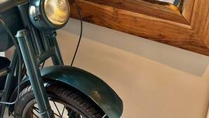 Una habitación con una cama, una motocicleta y un espejo que refleja la cama.