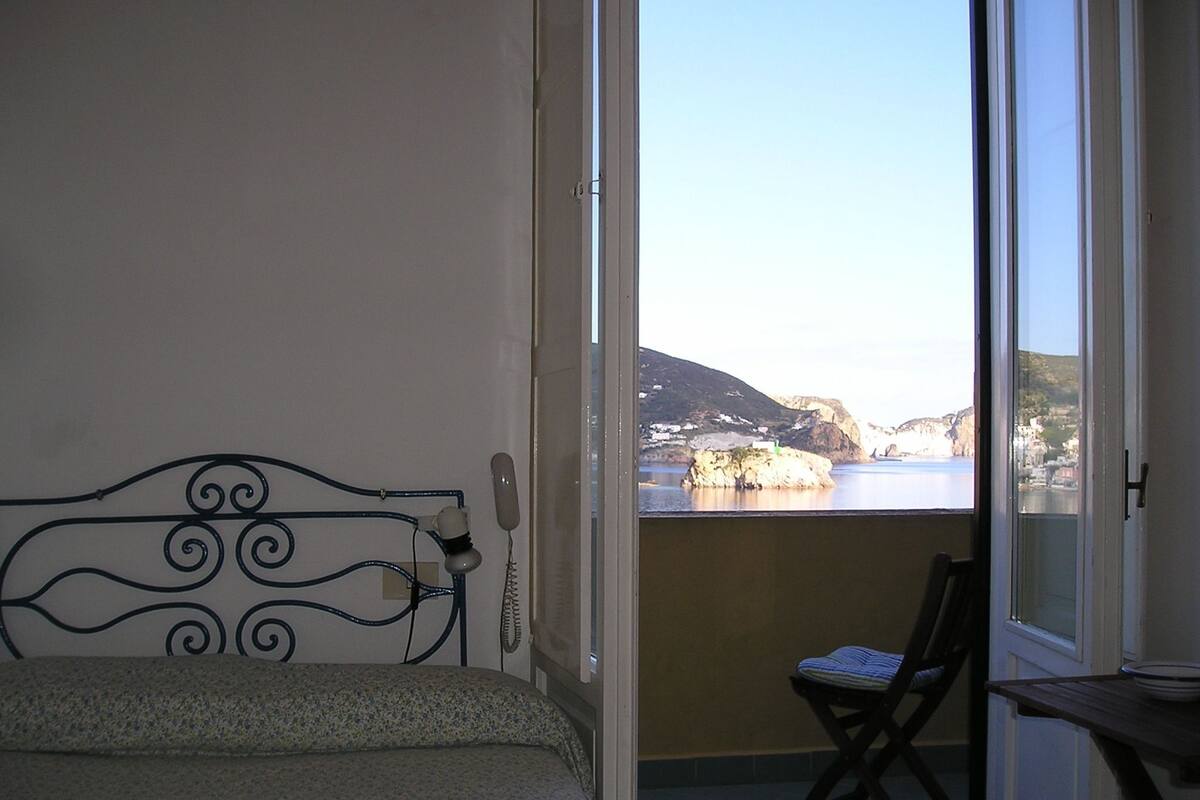 Un balcón con cama, una silla y una mesa.