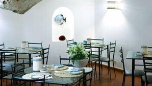 A dining area with tables and chairs, a potted plant, and a fish decoration on the wall.